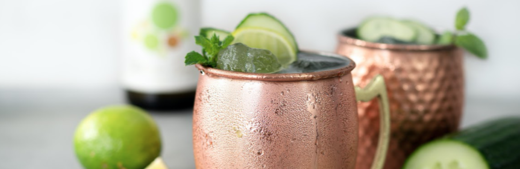 Kupfertassen mit Limetten, Gurken und Minze